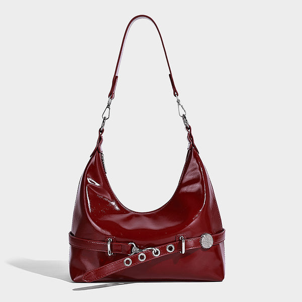 Glossy black slouchy hobo shoulder bag with silver-tone hardware, belt-style grommet strap at base, and long adjustable