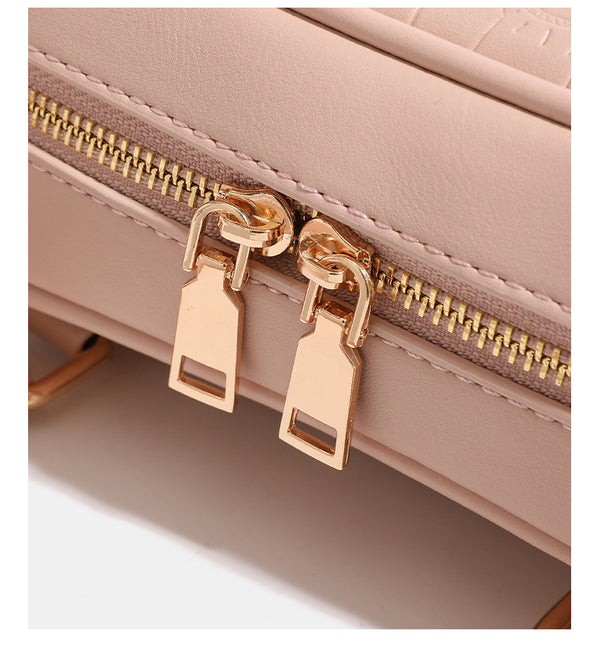 Mini croc-embossed barrel handbag with gold-tone hardware, dual zip top handles, detachable crossbody strap, and fluffy