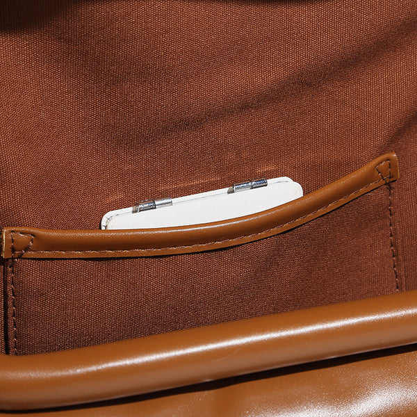 Compact structured baguette shoulder bag with smooth leather-look finish, zip top, and adjustable silver-buckle strap, detail