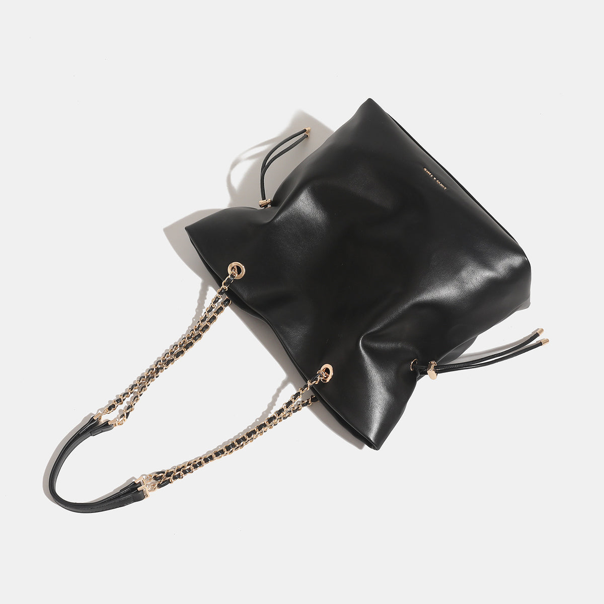 Soft-structured leather-look tote bag with gold-tone chain-and-strap shoulder handles and side drawstring cinches, detail
