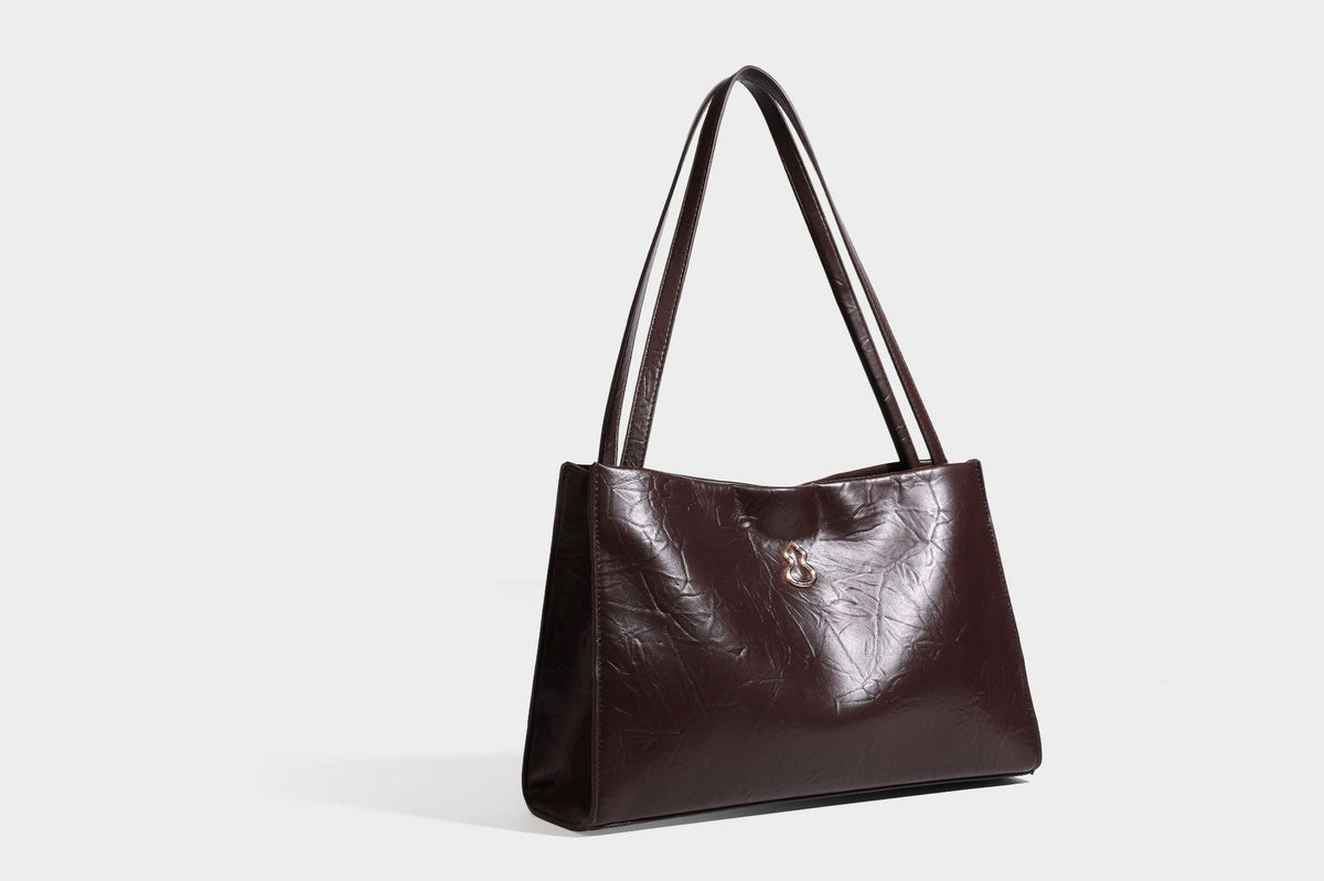 Strukturierte rechteckige Tote-Schultertasche aus glänzender, geknitterter Lederoptik mit langen Doppelträgern und Emblem in Goldoptik