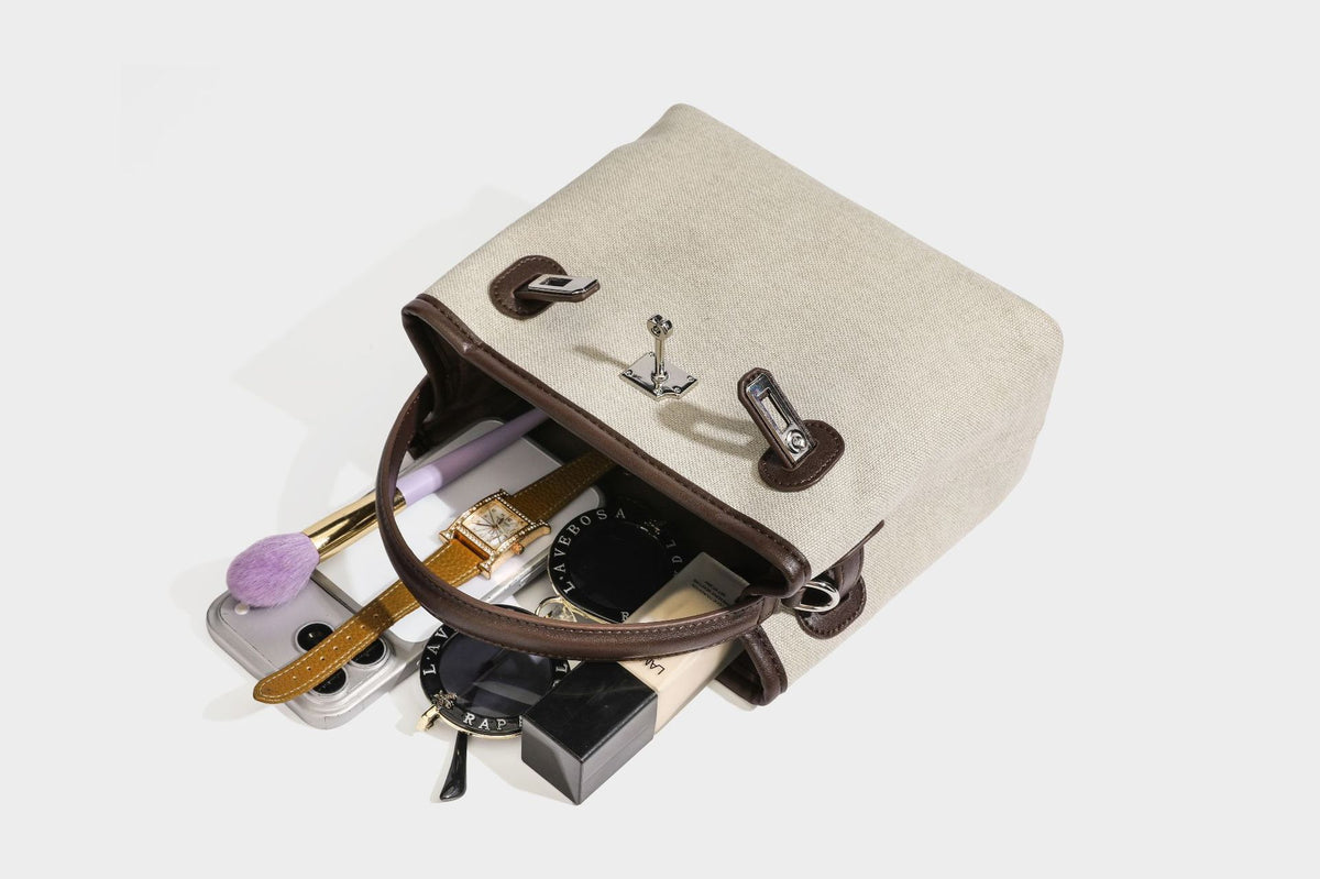 Small structured beige canvas top-handle bag with dark brown leather-look trim, silver turn-lock hardware, and detachable