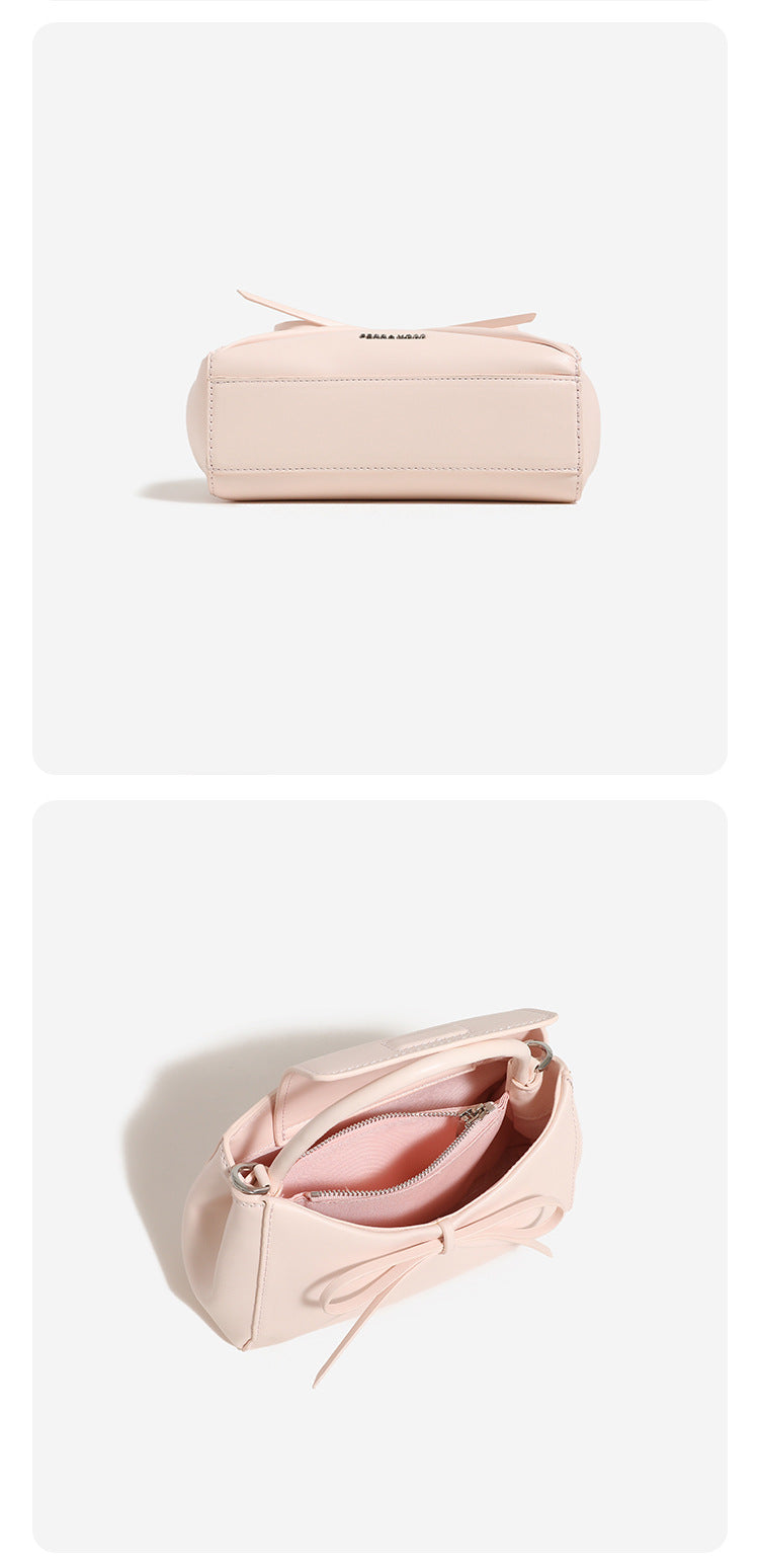 Structured mini trapezoid top-handle crossbody bag with sculpted bow front detail, smooth matte finish, silver-tone hardware