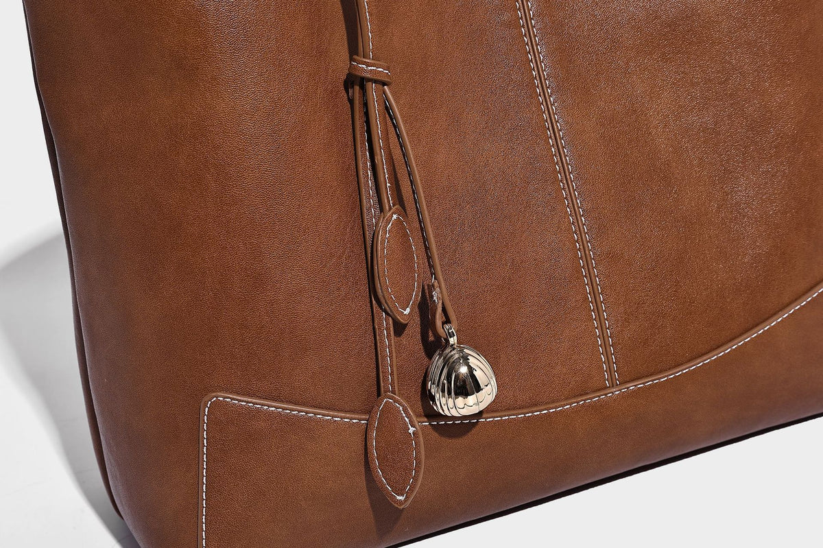 Große, strukturierte Schultertasche im Tote-Stil in Braun und Lederoptik mit langen Doppelriemen, Schnallenbeschlägen, Quasten-Anhänger und geschwungener