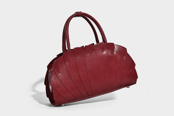 Structured dome satchel with fan-pleated leather-look exterior, dual top handles, and detachable shoulder strap, detail view