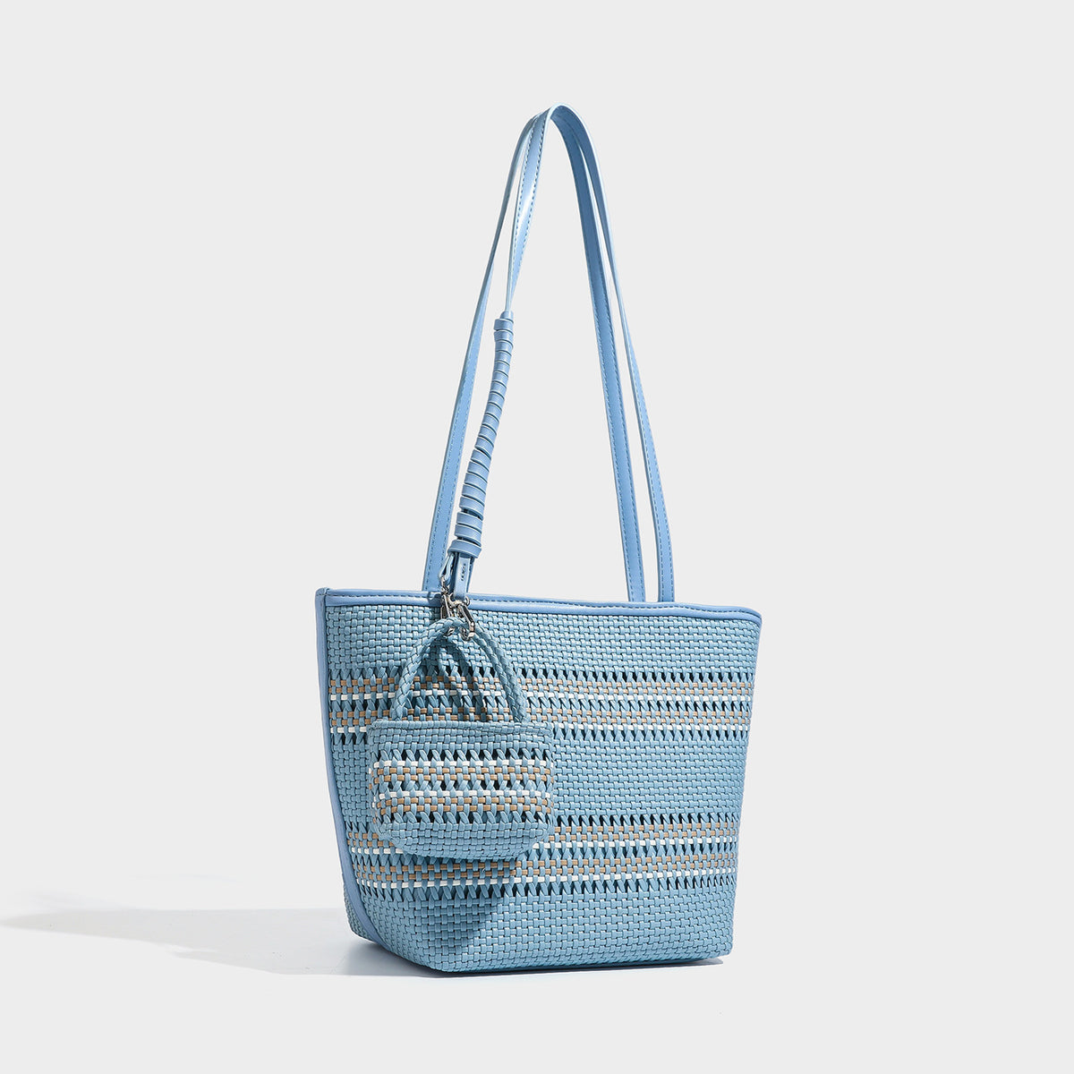 Large structured woven tote bag with striped basket-weave finish, long shoulder straps, and detachable mini pouch charm