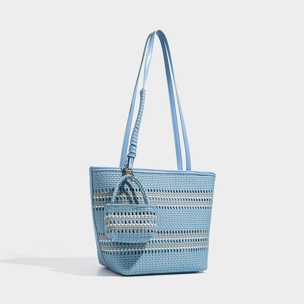 Large structured woven tote bag with striped basket-weave finish, long shoulder straps, and detachable mini pouch charm