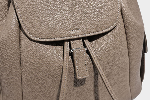 Compact pebbled leather-look flap drawstring backpack handbag with side pockets, top handle, and silver-tone hardware, detail