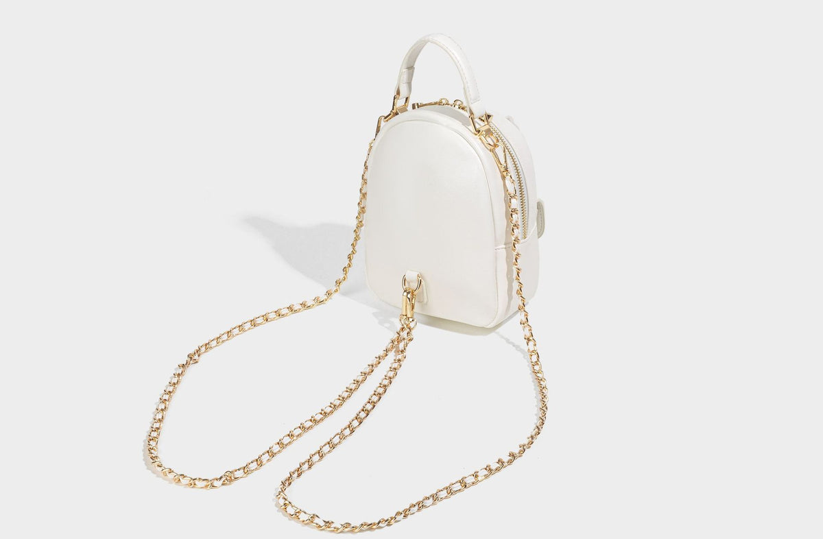 Structured mini backpack handbag with butterfly embroidery, gold-tone chain strap, and turn-lock front flap pocket, detail