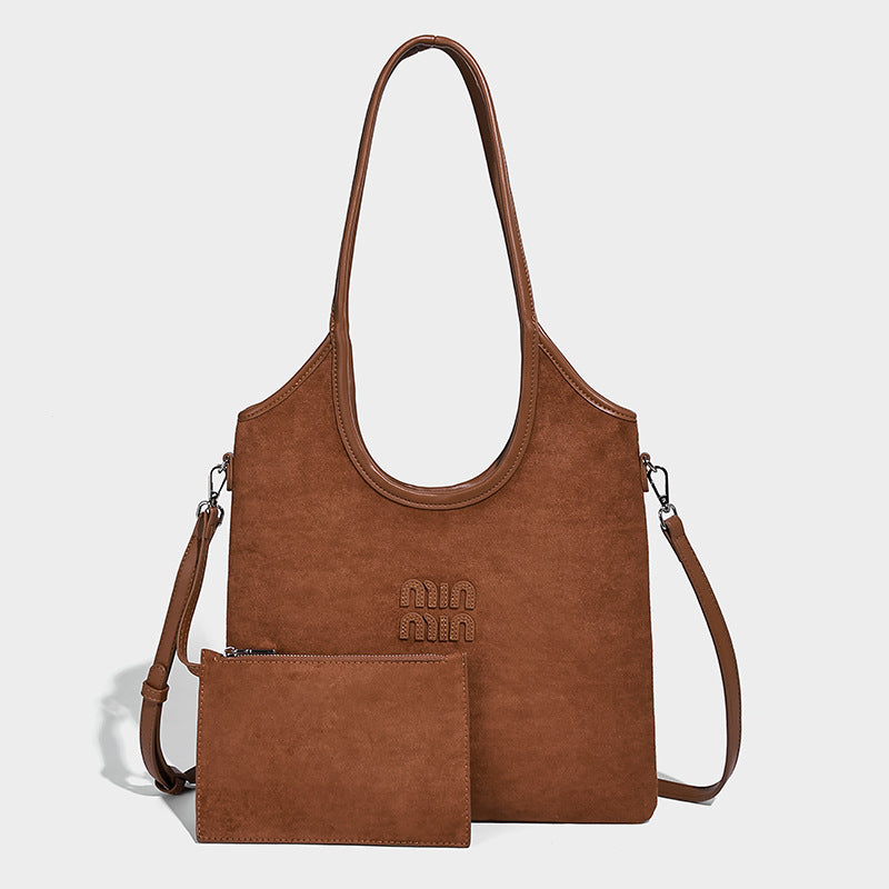 Warm brown matte suede-look tote bag with long top handles, embossed logo detail, silver-tone hardware, and matching, detail