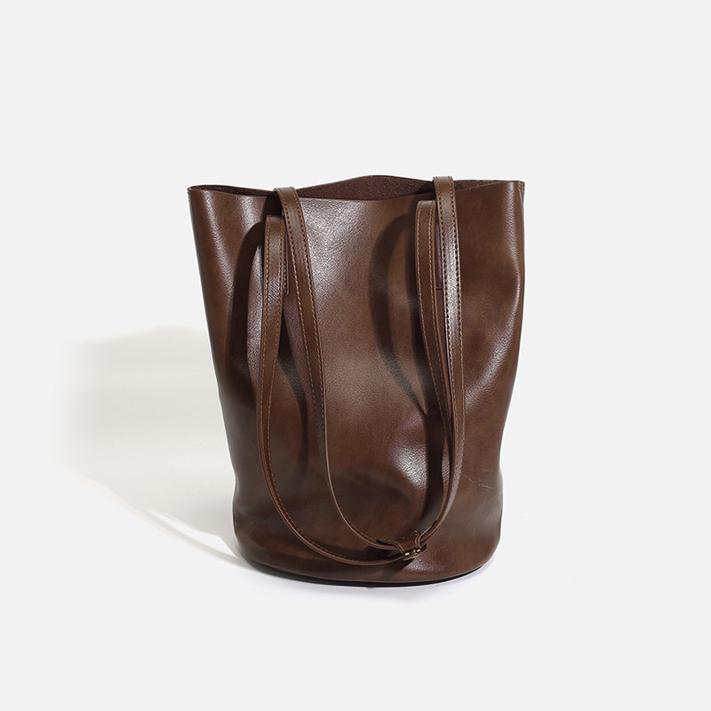 Large black smooth leather-look bucket tote bag with long shoulder straps and open top, front view