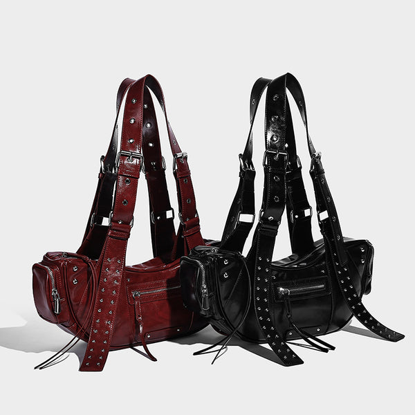 Glossy black crescent shoulder bag with silver-tone rivets, multiple zip pockets, and long adjustable studded straps, detail