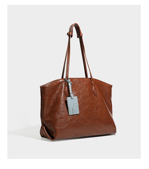 Übergroße, weich fallende Tote-Bag in dunklem Bordeauxrot mit glänzender, geknautschter Lederoptik, zwei langen Schulterriemen und Kontrast