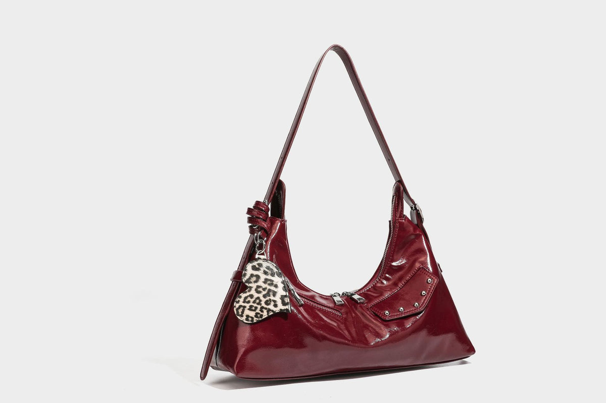 Glossy dark brown hobo shoulder bag with slim strap, front zip pocket, stud detail, and detachable leopard-print heart charm