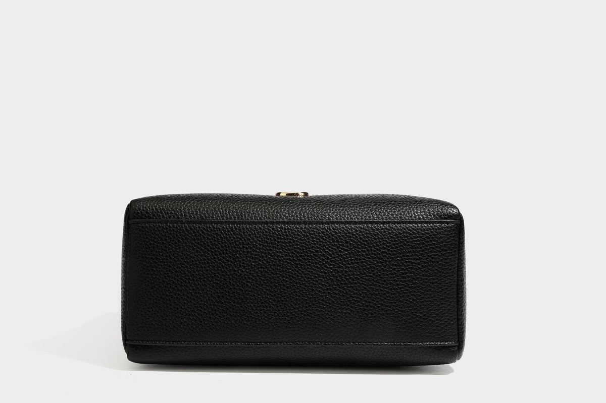 Small structured pillow satchel bag with pebbled leather-look finish, dual rolled top handles, gold-tone gourd emblem, and