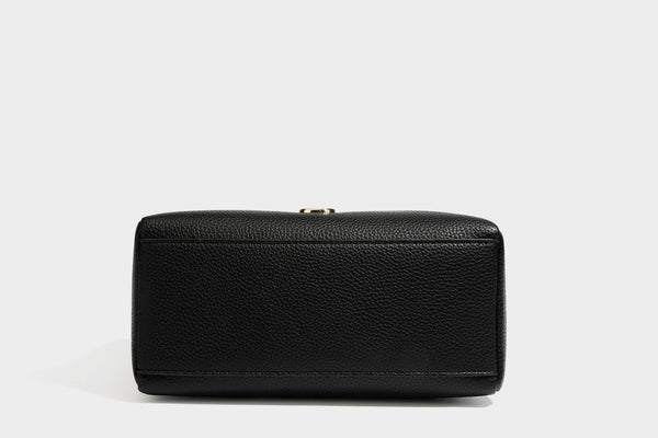 Small structured pillow satchel bag with pebbled leather-look finish, dual rolled top handles, gold-tone gourd emblem, and