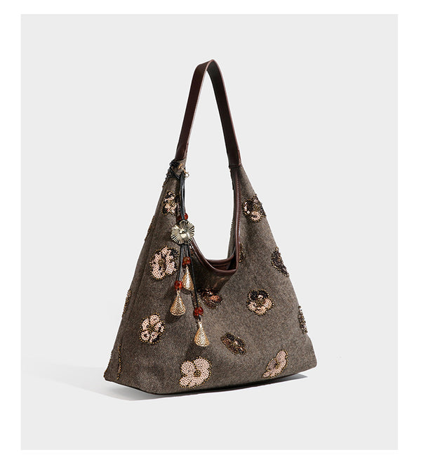 Lässig fallende, trapezförmige Schulter-Tote in Anthrazitgrau mit floralen Paillettenmotiven in Silber, Riemen in Lederoptik und herabhängendem Perlenbesatz