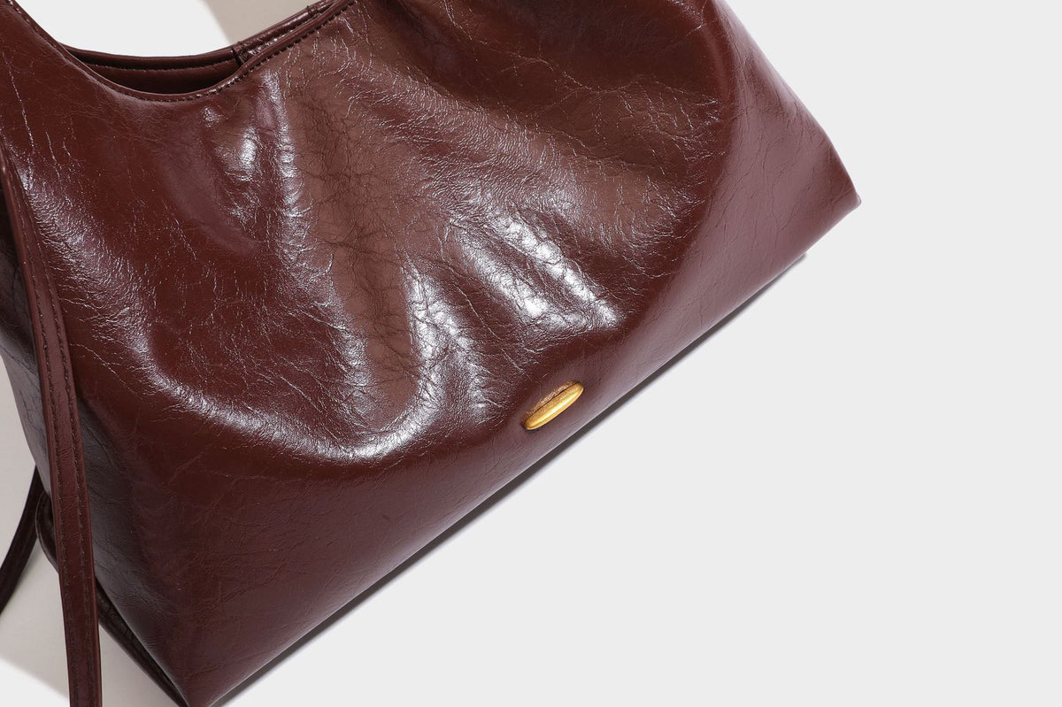Locker fallende Hobo-Schultertasche mit offenem Oberteil aus glänzendem, geknautschtem Lederimitat in Dunkelbraun, mit schmalem verstellbarem Riemen und goldfarbenem