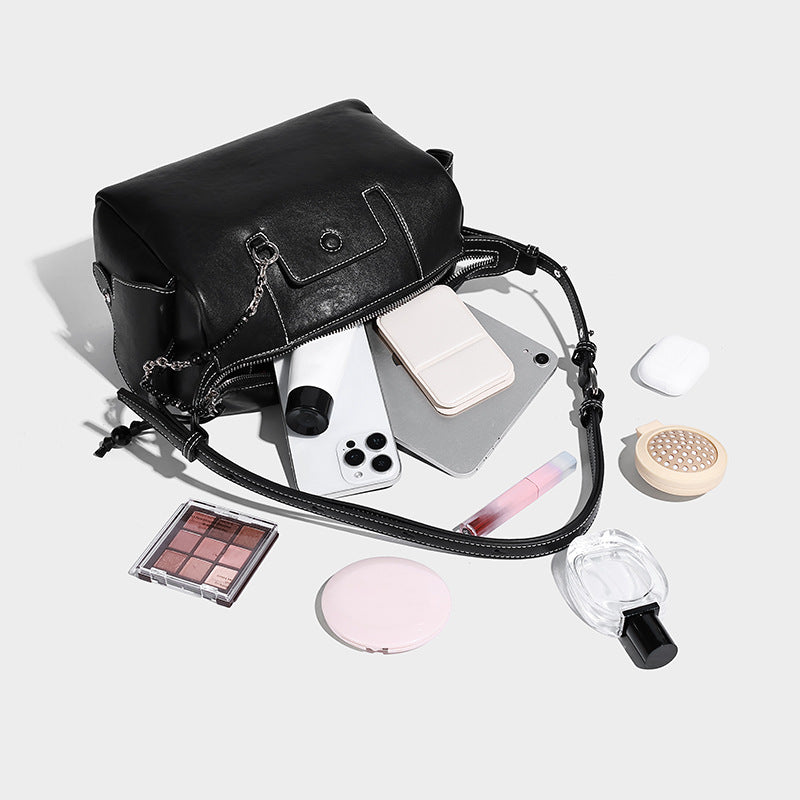 Small slouchy moto-style crossbody bag in smooth matte leather-look finish with white contrast stitching, silver-tone, detail