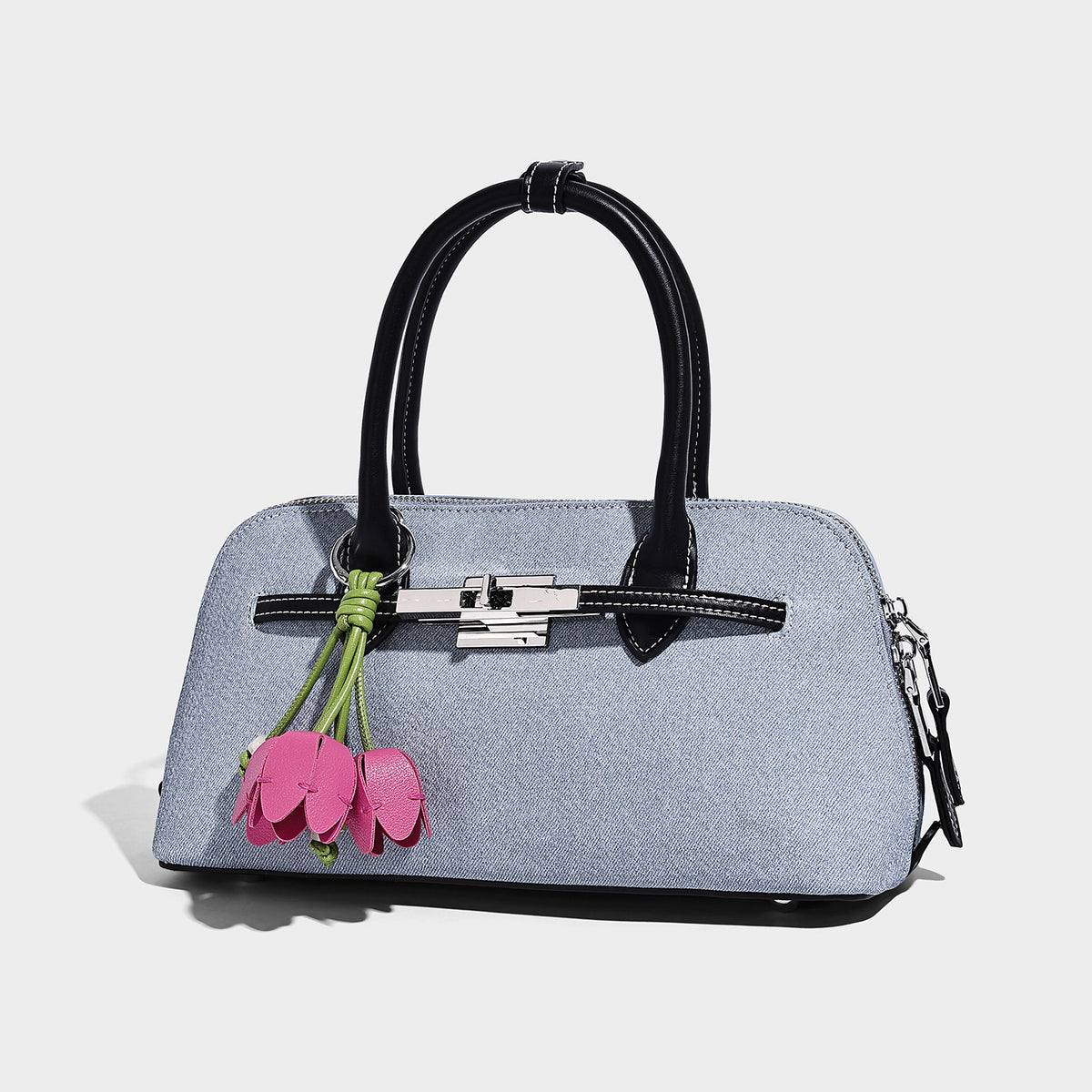 Compact structured satchel in light blue denim-look fabric with black leather-look trim, silver turn-lock closure, rolled