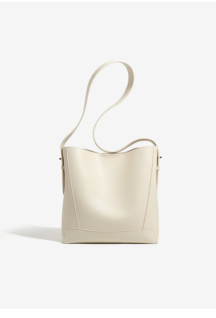 Structured smooth leather-look bucket shoulder bag with long adjustable strap and gold-tone buckle hardware in brown, detail