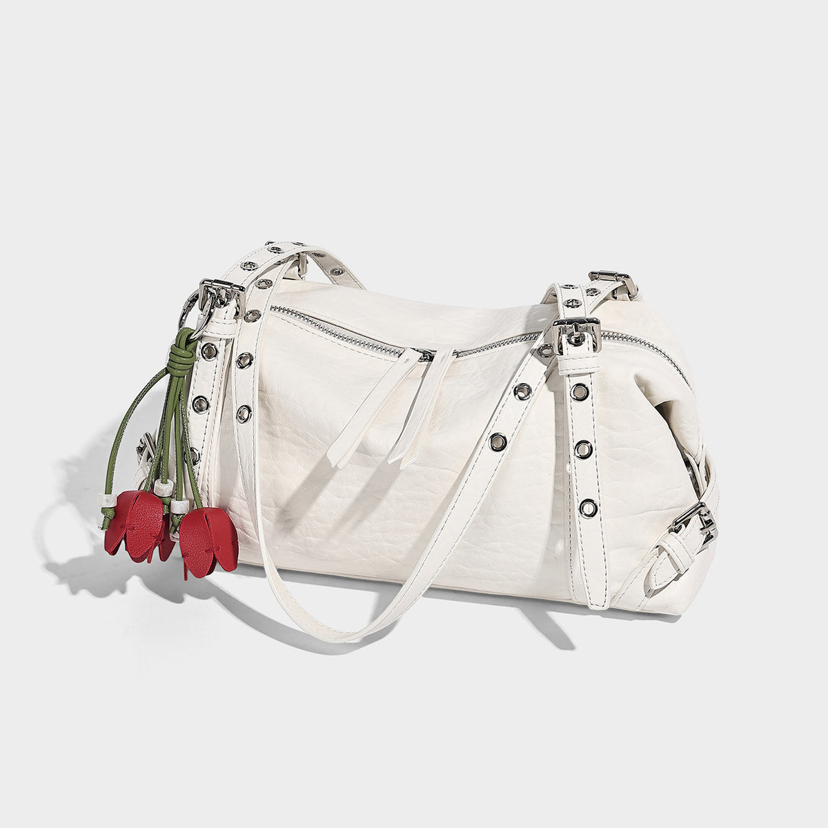 Pale yellow leather-look barrel bag with silver grommet-studded shoulder straps, top zip closure, and pink tulip floral