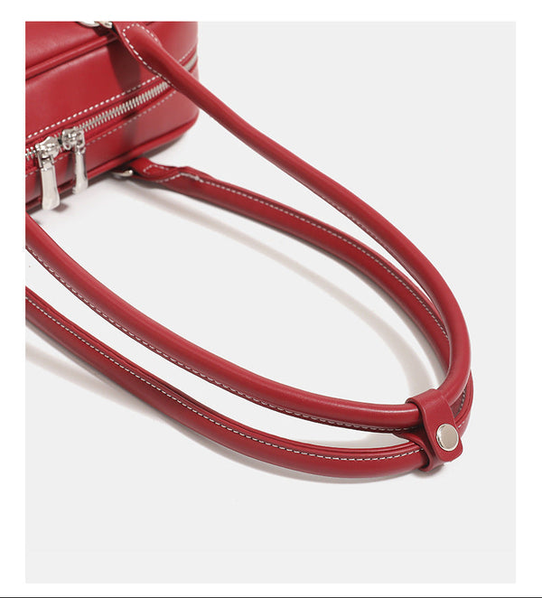 Compact rounded baguette shoulder bag with smooth leather-look finish, slim double straps, silver-tone zipper hardware, and