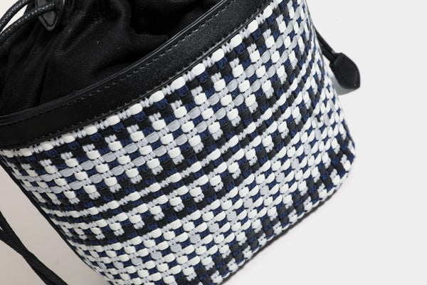 Small structured woven checker bucket bag with braided top handle, drawstring closure, and silver-tone hardware in black