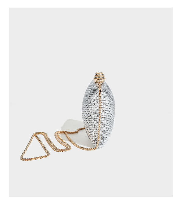 Small structured rectangular metallic woven-texture clutch bag with jeweled knob clasp and gold-tone chain strap, detail view