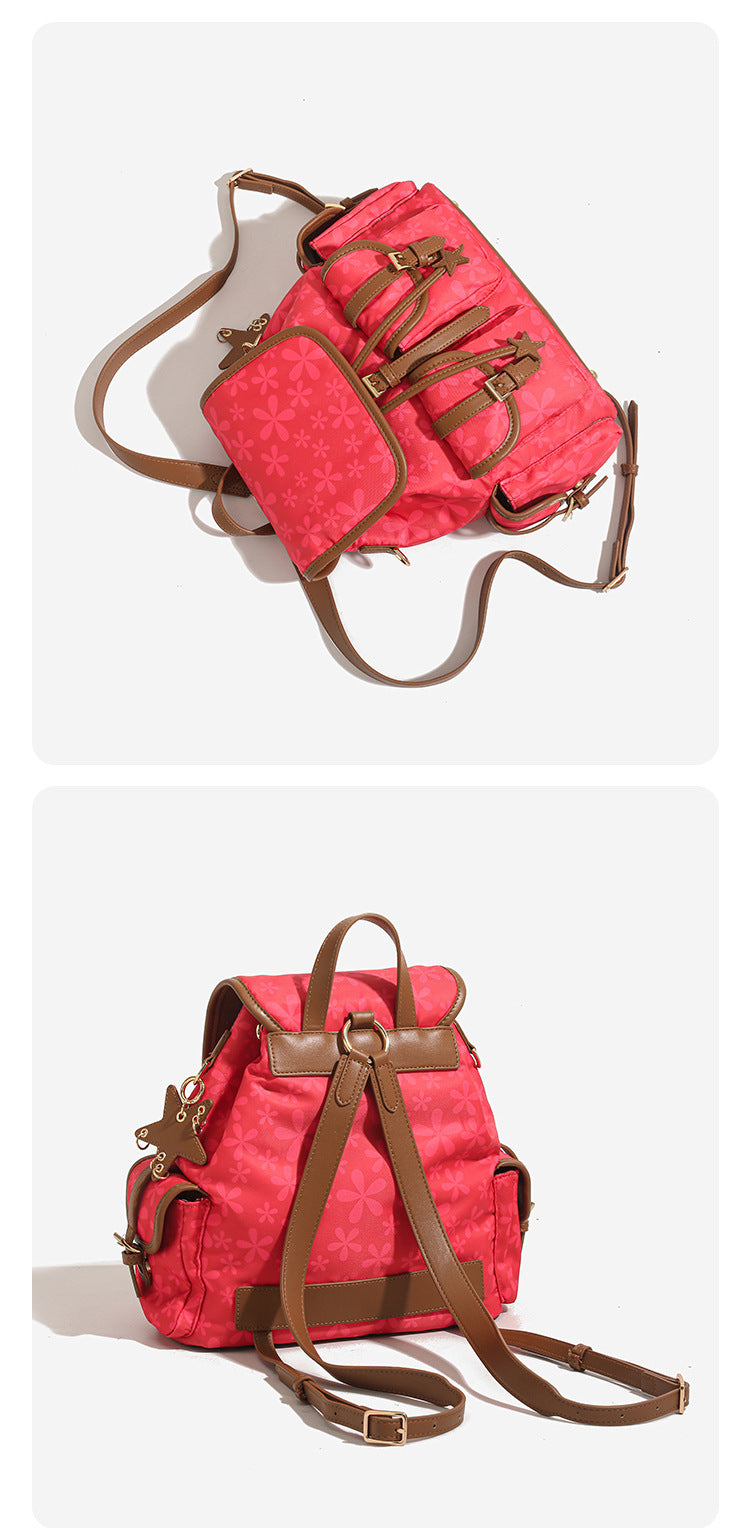 Red floral-print backpack handbag with brown leather-look trim, dual front buckle pockets, star charms, and gold-tone, detail