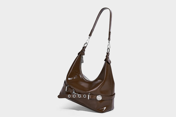 Glossy black slouchy hobo shoulder bag with silver-tone hardware, belt-style grommet strap at base, and long adjustable