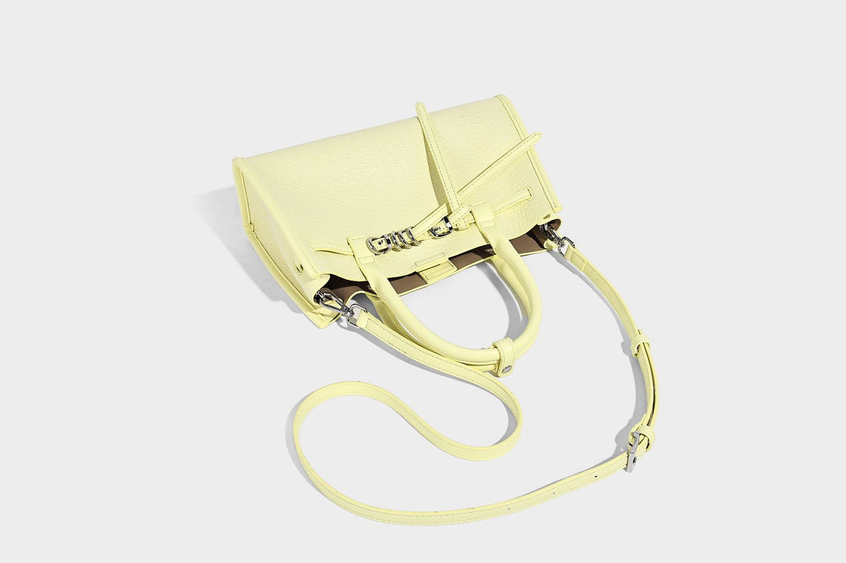 Structured trapezoid tote bag in pebbled leather-look finish with double top handles, silver-tone bar hardware, and, detail