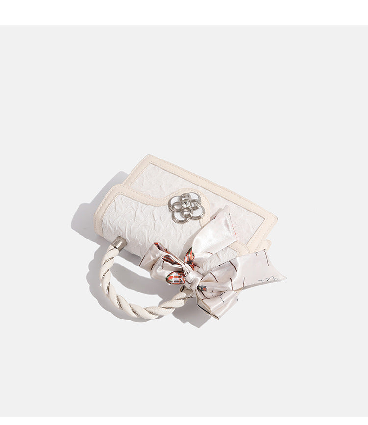 Ivory structured mini crossbody bag with crinkled leather-look finish, silk scarf top handle, silver four-petal flower clasp