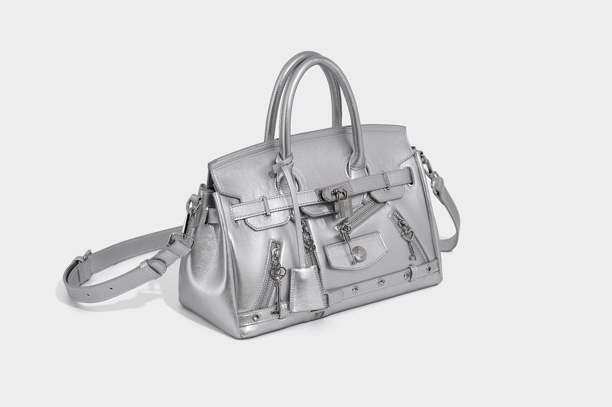 Structured black leather-look satchel bag with silver padlock hardware, front zip pockets, key charms, and top handles