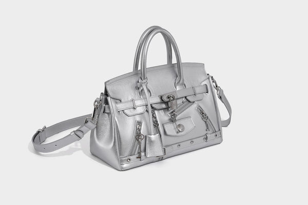 Structured black leather-look satchel bag with silver padlock hardware, front zip pockets, key charms, and top handles