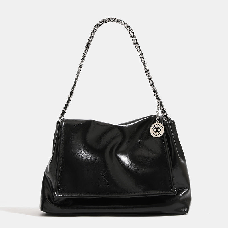 Soft trapezoidal chain-strap shoulder bag with foldover flap and circular logo medallion, detail view 8