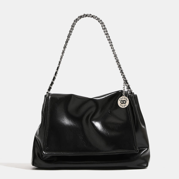Soft trapezoidal chain-strap shoulder bag with foldover flap and circular logo medallion, detail view 8