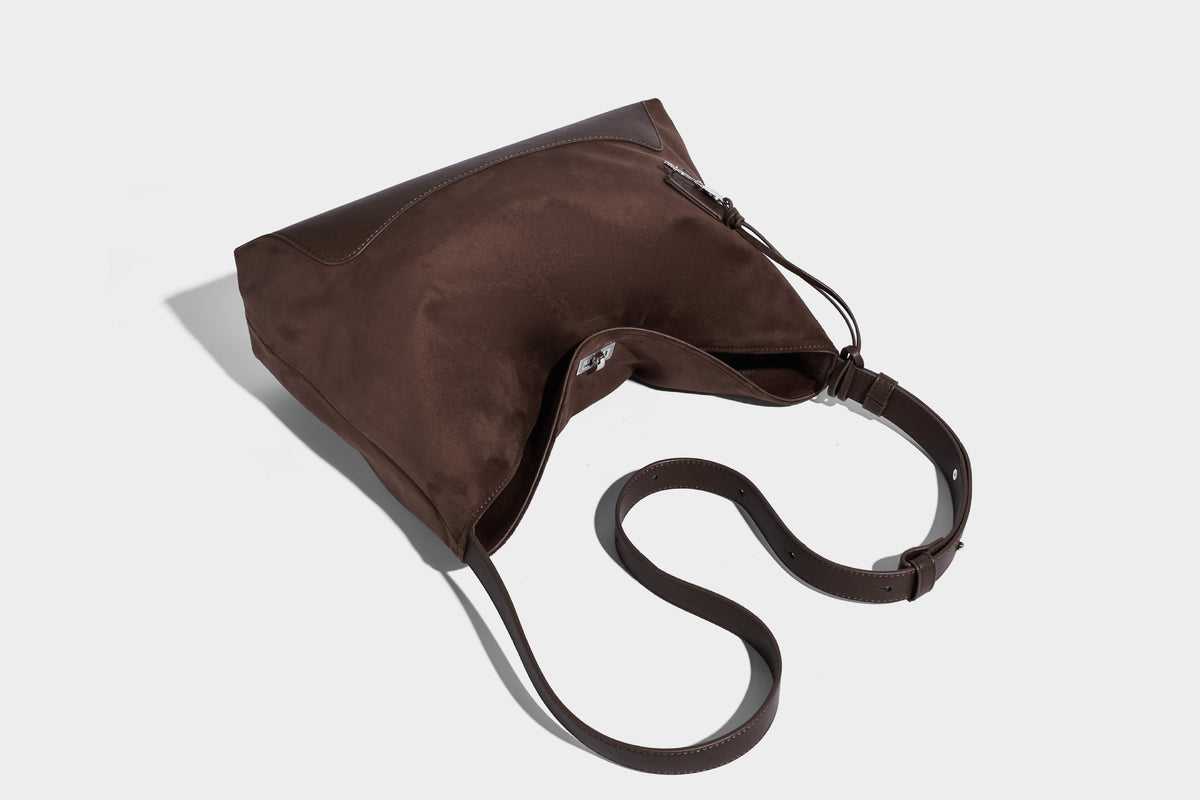 Dark brown slouchy hobo bag with matte suede-look body, smooth leather-look base trim, adjustable shoulder strap, and, detail