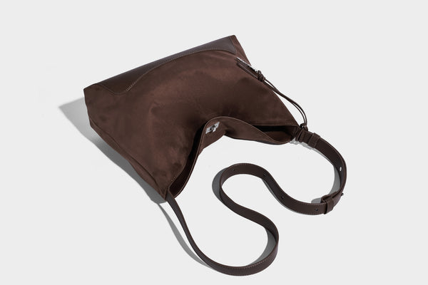 Dark brown slouchy hobo bag with matte suede-look body, smooth leather-look base trim, adjustable shoulder strap, and, detail