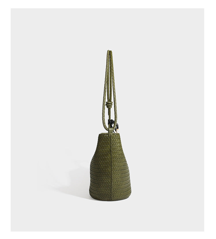 Olive green woven leather-look bucket bag with braided crossbody strap, knotted adjustment, and gold-tone tassel charm with