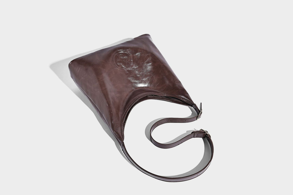 Glossy slouchy hobo shoulder bag with adjustable strap and embossed floral emblem, detail view 27