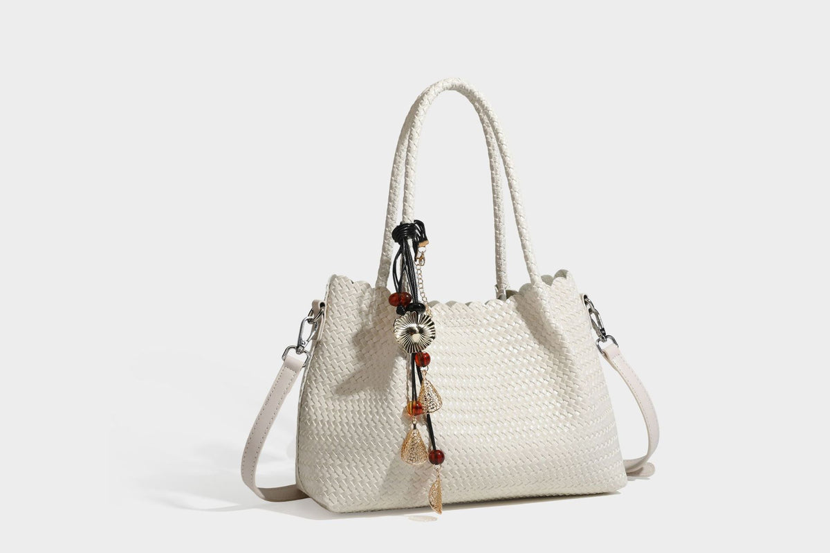 Strukturierter, glänzend geflochtener Shopper mit Muschelkantenabschluss am oberen Rand, geflochtenen Tragegriffen, abnehmbarem Crossbody-Riemen und Perlenquaste