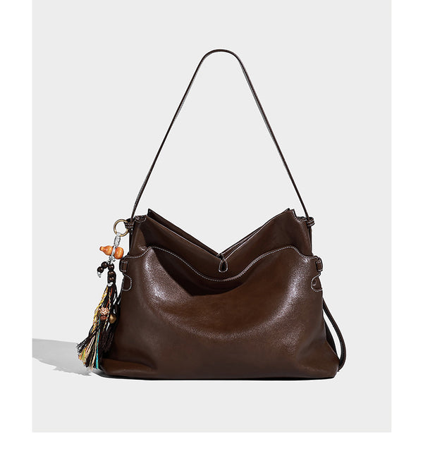 Large slouchy leather-look hobo tote bag with open top, adjustable shoulder strap, and colorful tassel bead charm, detail