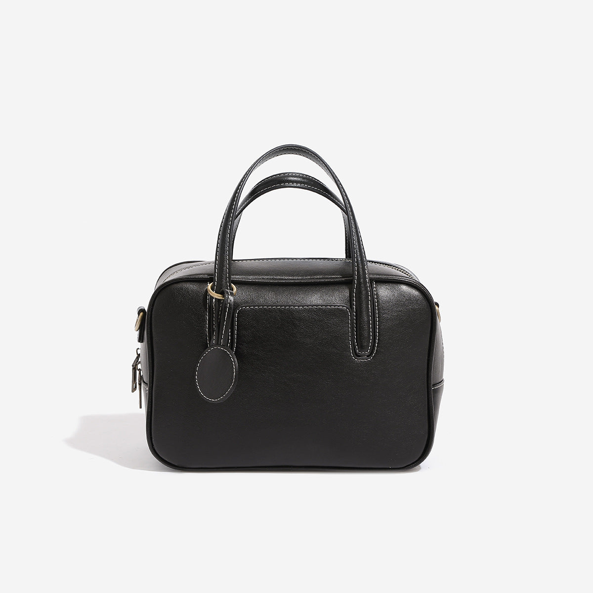 Structured boxy bowling-style tote bag in deep brown leather-look finish with dual top handles, front slip pocket, round