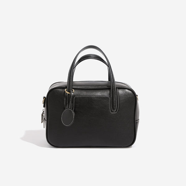 Structured boxy bowling-style tote bag in deep brown leather-look finish with dual top handles, front slip pocket, round