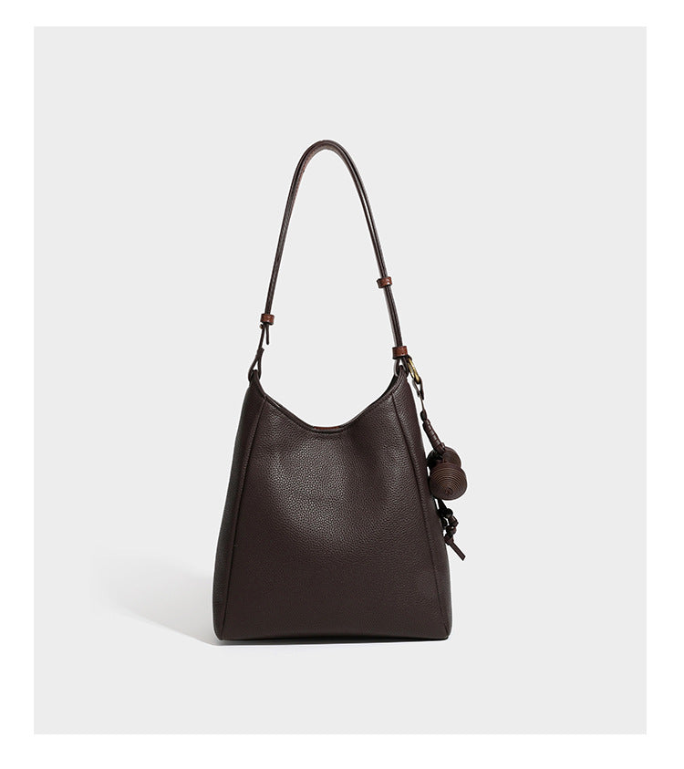 Hobo-Schultertasche in dunklem Espresso mit genarbter Oberfläche, warmen cognacfarbenen Details, verstellbarem schmalem Riemen, goldfarbenen Ringbeschlägen und geknotetem