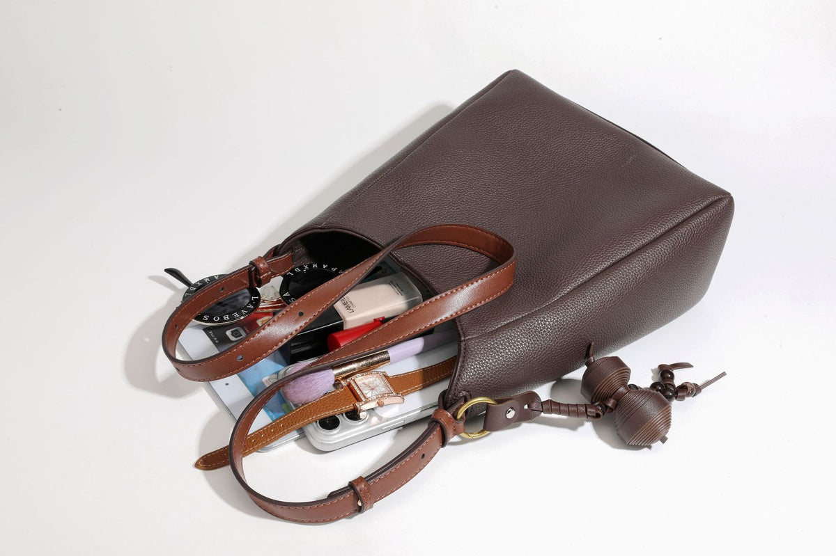 Dunkel espressofarbene, genarbte Hobo-Schultertasche mit warm camelbraunen Details, verstellbarem schmalem Riemen, goldfarbenen Ringbeschlägen und geknotetem