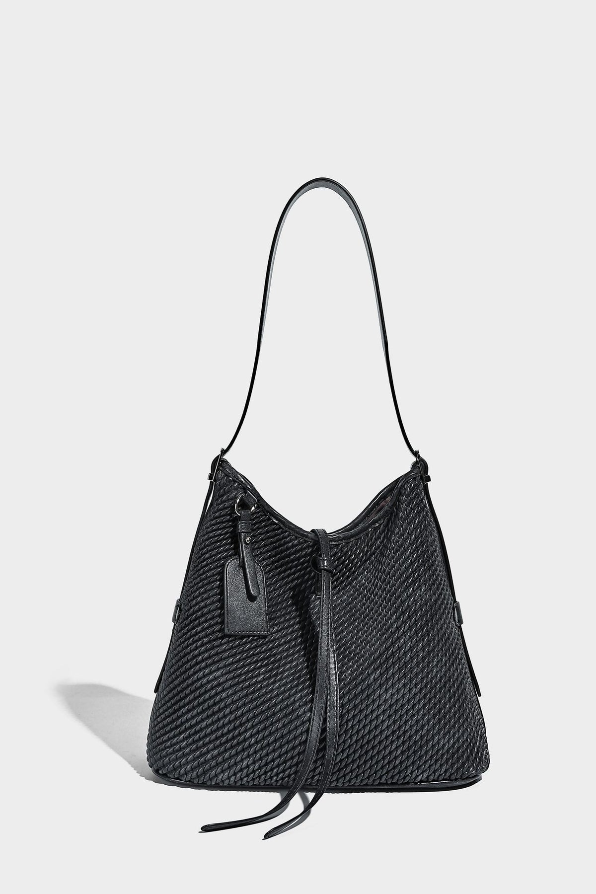 Große Schultertasche im Beuteltaschenstil mit Flechtstruktur, glatten Besätzen in Lederoptik, verstellbarem Riemen und Anhänger-Detail, Detailansicht