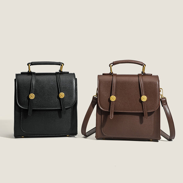 Structured mini satchel backpack with smooth leather-look finish, front flap pocket, gold-tone stud closures, and top handle