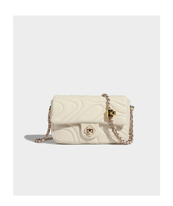 Compact cream quilted flap crossbody bag with wave stitching, gold-tone chain strap, and four-petal turn-lock clasp, detail